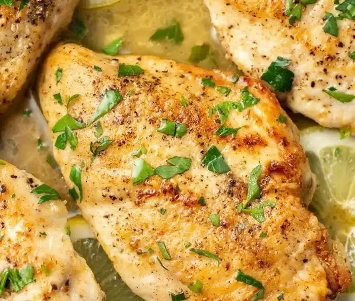 Plate of easy lemon chicken garnished with herbs and lemon wedges