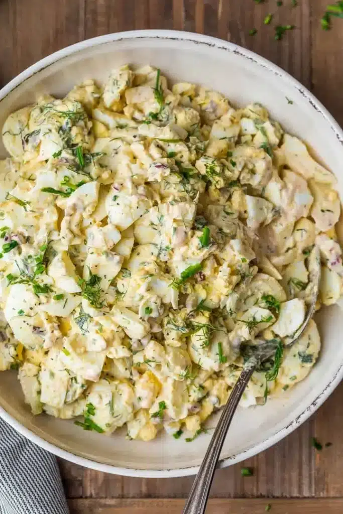 Delicious homemade egg salad in a bowl with fresh herbs and spices.