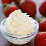 A bowl of homemade whipped cream topped with fresh strawberries.