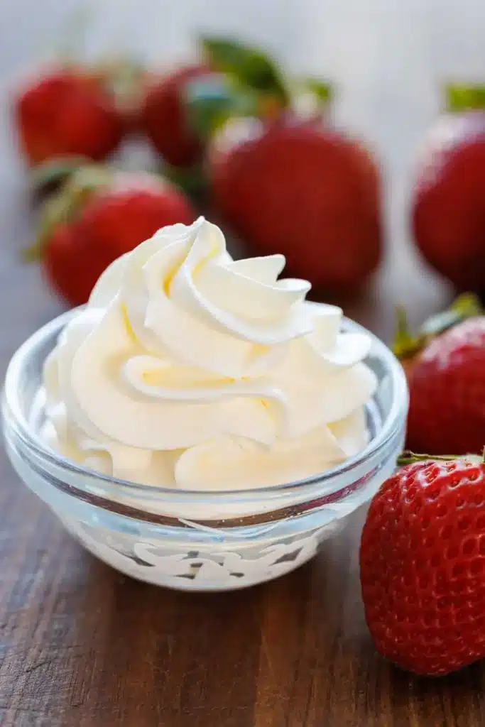 A bowl of homemade whipped cream topped with fresh strawberries.