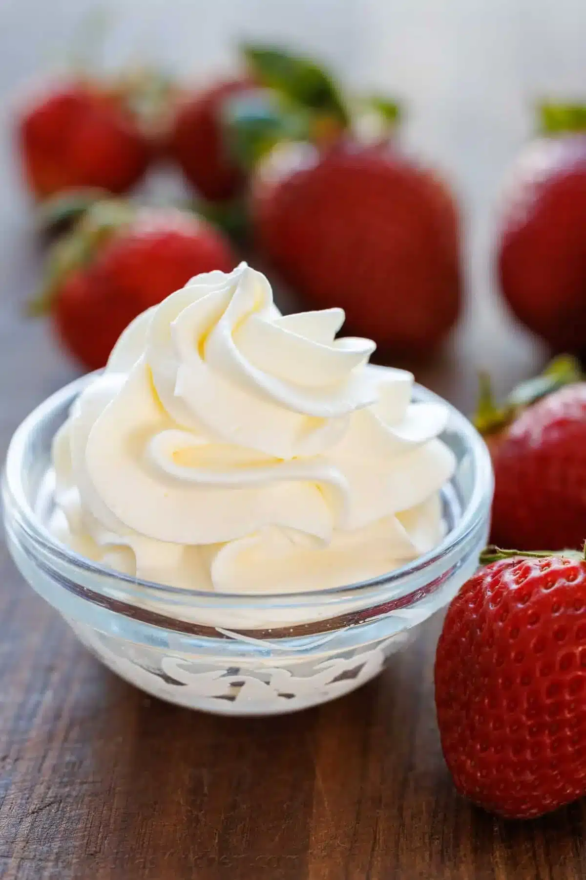 A bowl of homemade whipped cream topped with fresh strawberries.