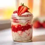 Bowl of strawberries and cream overnight oats topped with fresh strawberries