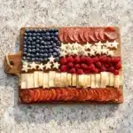 American Flag Charcuterie Board featuring cheeses, meats, and colorful fruits